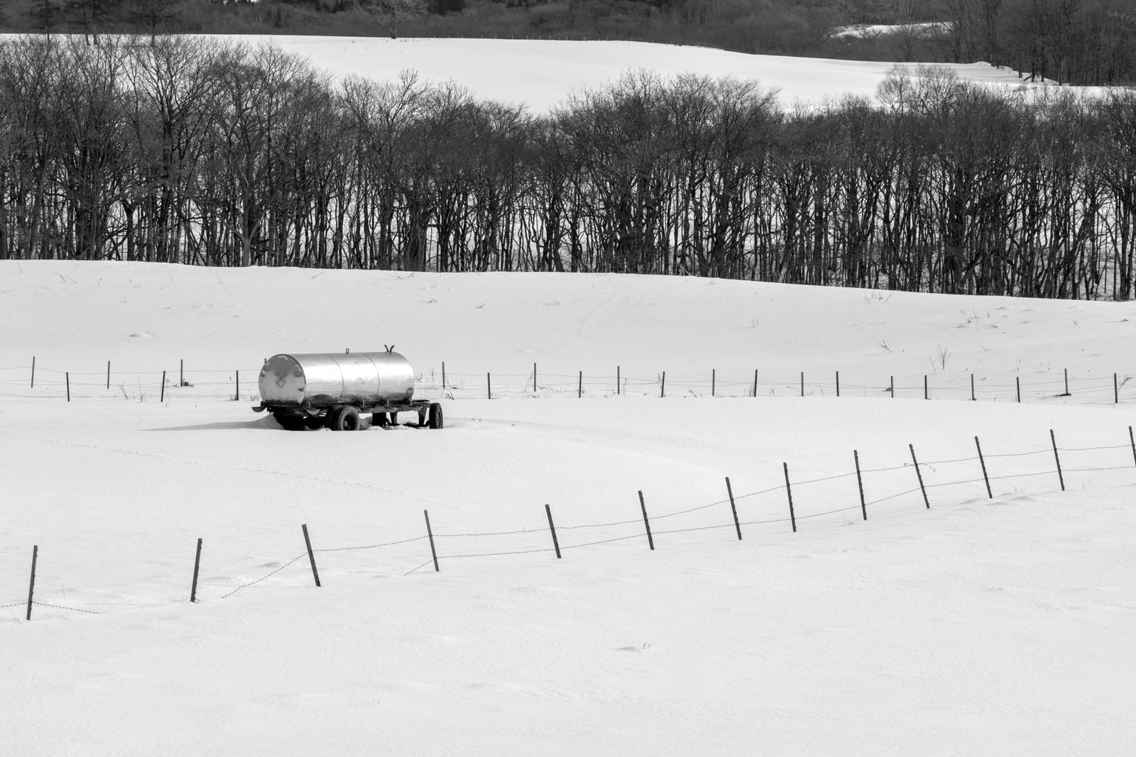 別海町の雪原に置かれたタンク車と木立